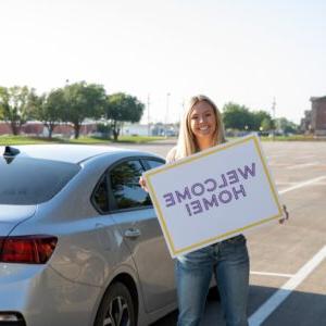 Young woman with a Welcome Home sign.